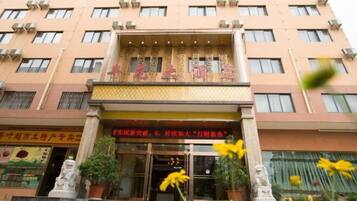 A hotel entrance with a signboard, steps leading up to the entrance, and two statues on either side.