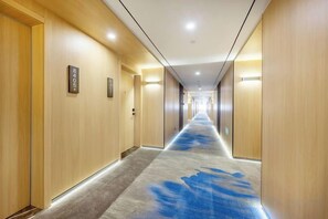 Een hotelgang met houten wanden, een vloerkleed en deuren met kamer nummers.
