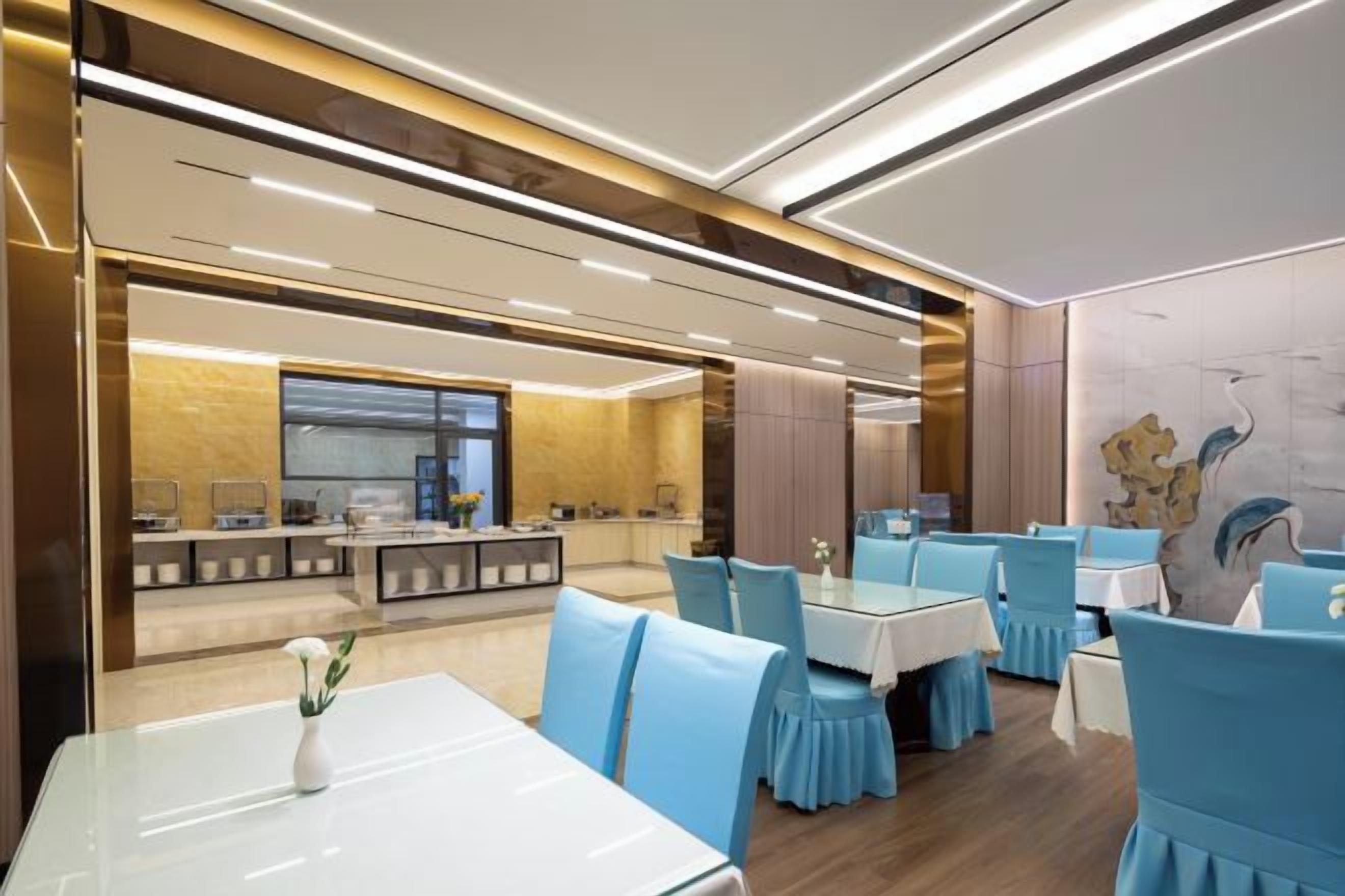 A modern restaurant interior with a bar area, dining tables, and blue chairs.