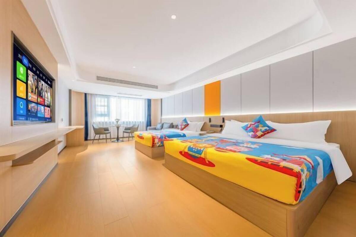 A hotel room with a large bed, a desk, and a TV mounted on the wall.