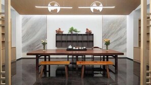 A modern dining area with a marble wall, wooden table, benches, and a shelf with decorative items. - Kunming Panlong Days Inn Selected Wyndham Hotel (Agricultural University Branch) (Kunming)