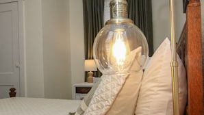 Un lit bien fait, avec une couverture matelassée, une table de chevet avec une lampe et une tête de lit en bois.