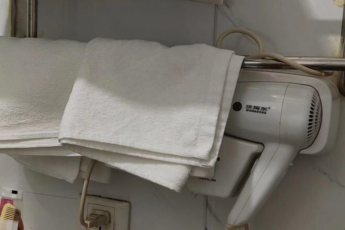 A hair dryer with a label, a towel, and a power outlet.