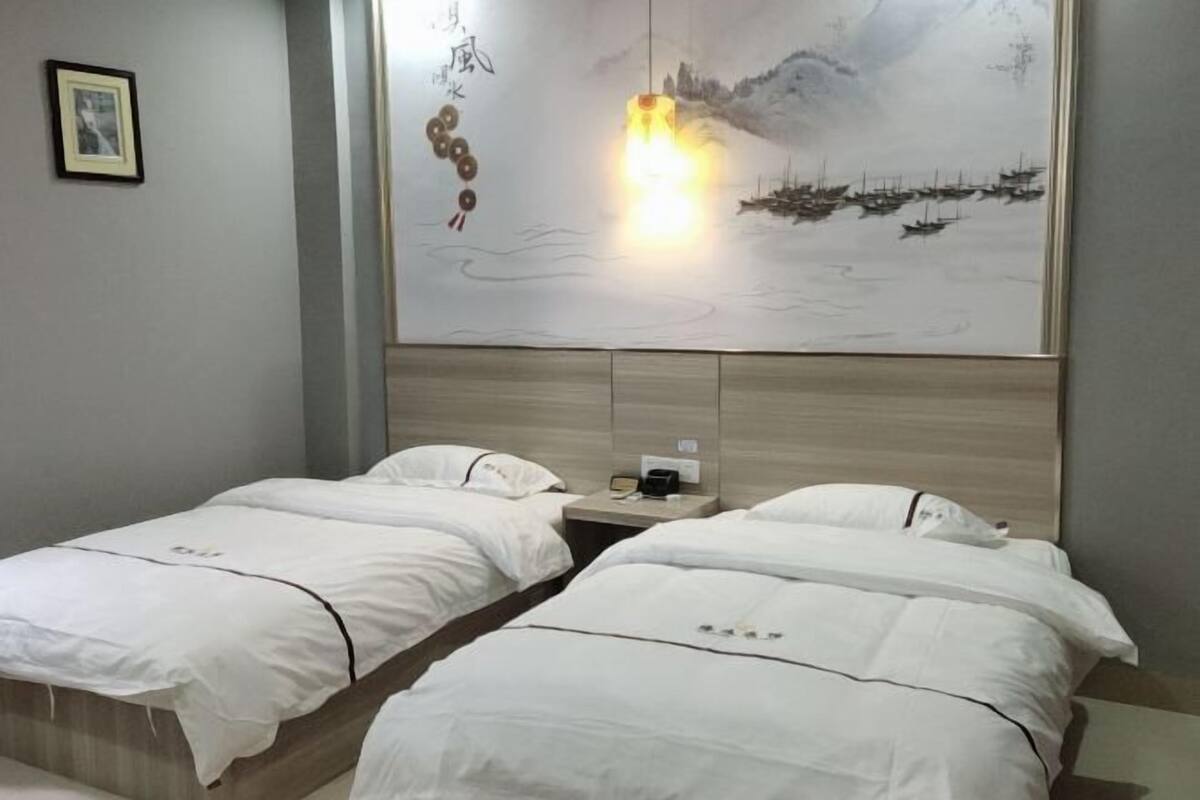 Habitación de hotel con dos camas, un cuadro y una mesita de noche.