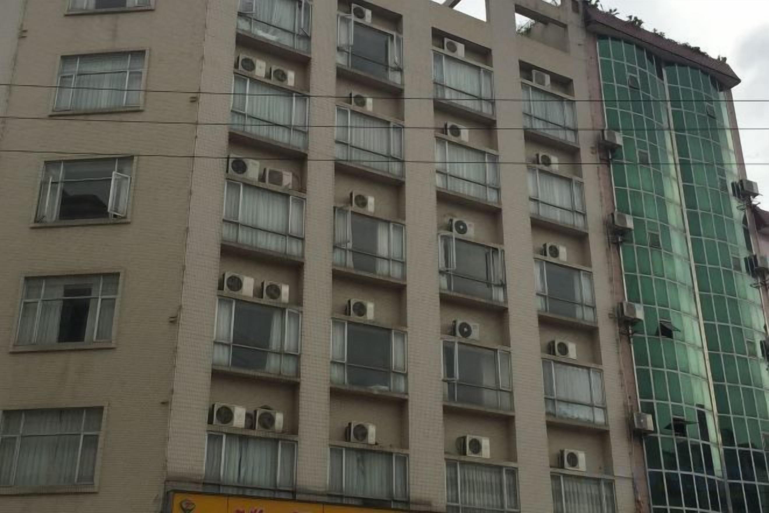 A multi-story building with numerous windows and air conditioning units.