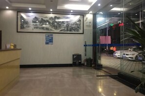 Un'area di accoglienza con una scrivania, un'opera d'arte incorniciata al muro, una porta vetrata che dà su un'esposizione di auto e un segnale direzionale blu.