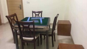 A dining area with a green pool table, four wooden chairs, and a small wooden cabinet. - Tengyun Hotel (Huaiji)