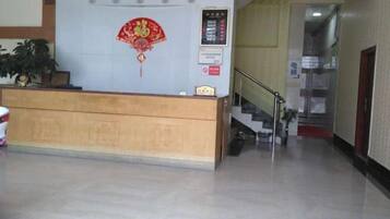 A reception desk with a clock, a red decorative fan, and a staircase leading to an upper floor.