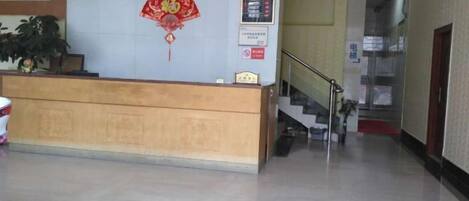 A reception desk with a clock, a red decorative fan, and a staircase leading to an upper floor.