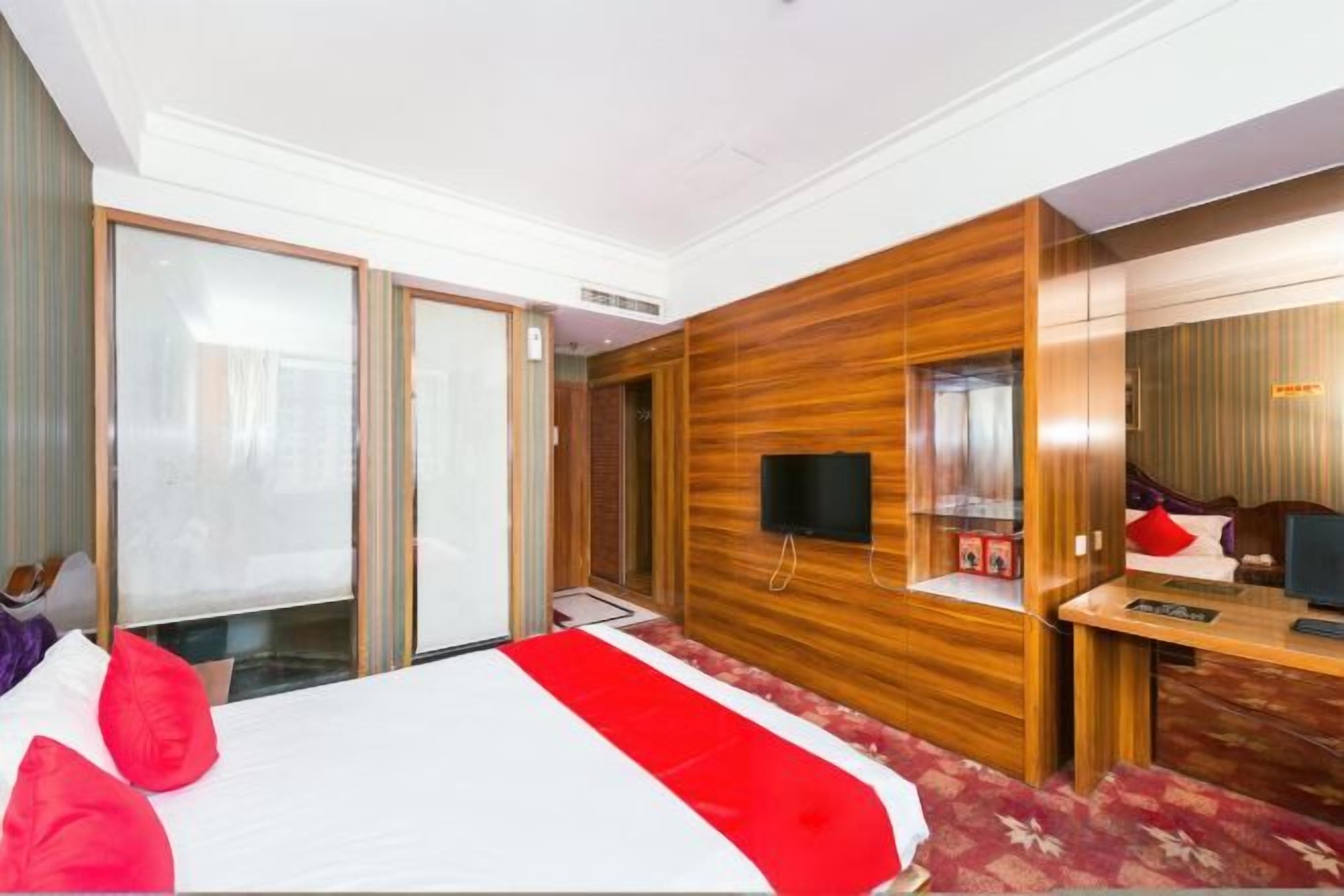 Une chambre d’hôtel avec un lit, un bureau, une télévision et une porte coulissante.