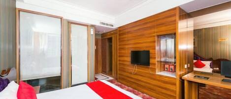 Une chambre d’hôtel avec un lit, un bureau, une télévision et une porte coulissante.