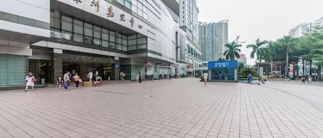 A modern building with a large entrance and a tiled plaza in front.