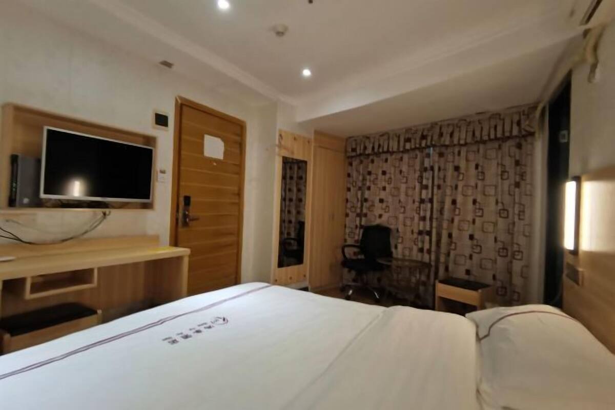Habitación de hotel con cama, televisión, escritorio y silla.