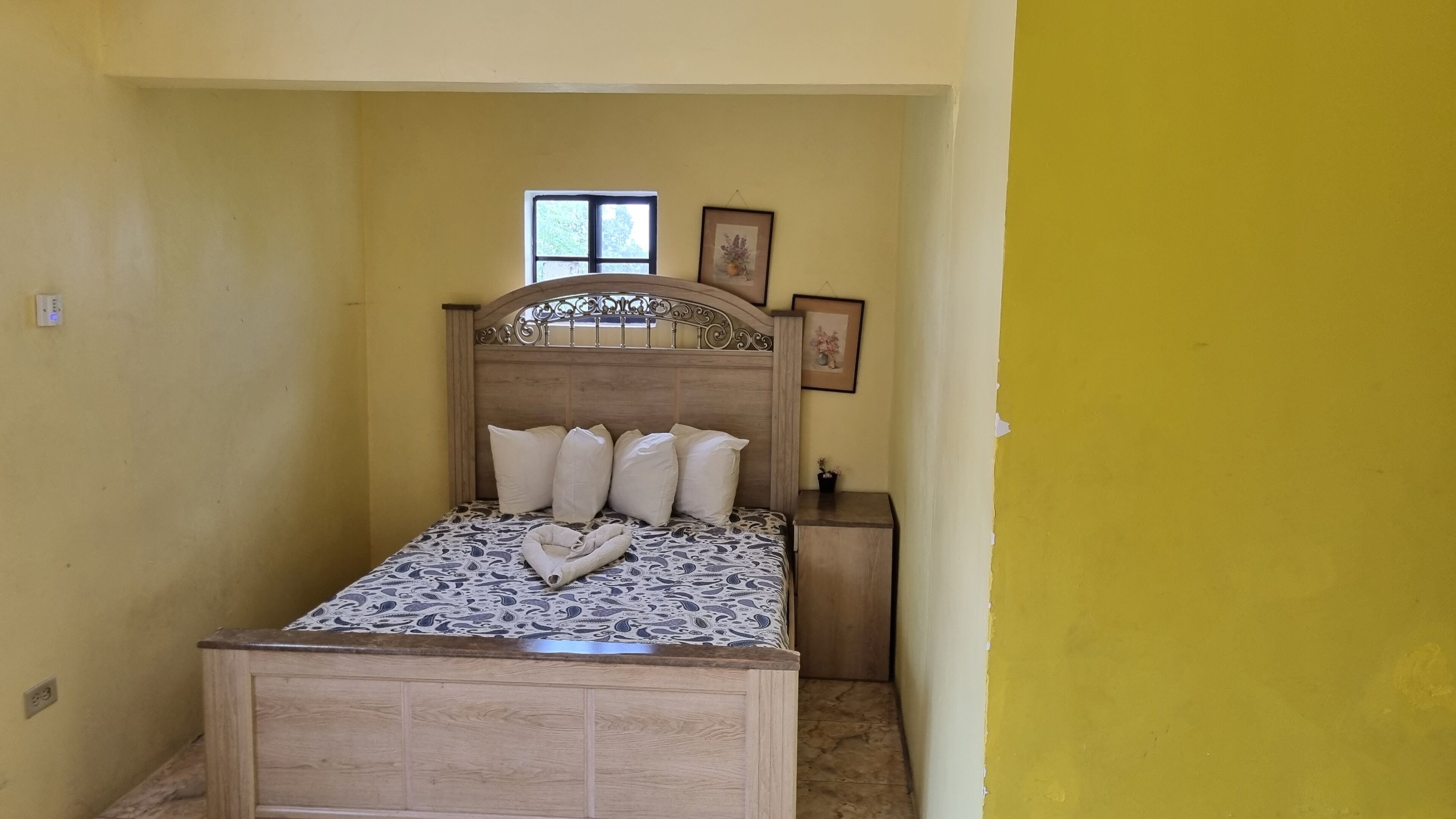 A room with a bed, a small window, and a framed picture on the wall.