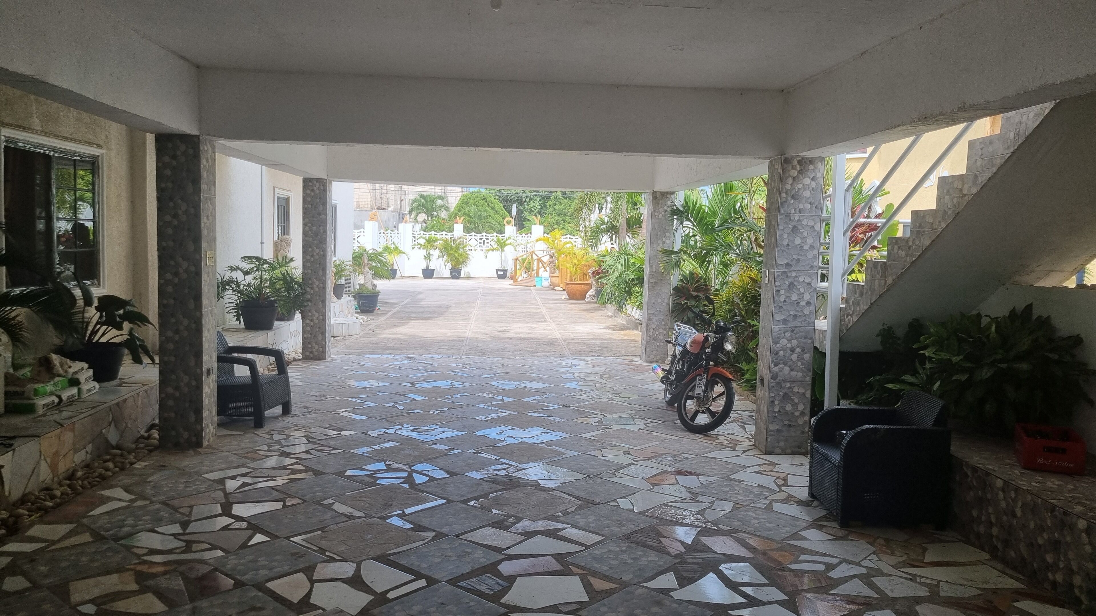 A covered outdoor area with a tiled floor leading to a staircase.