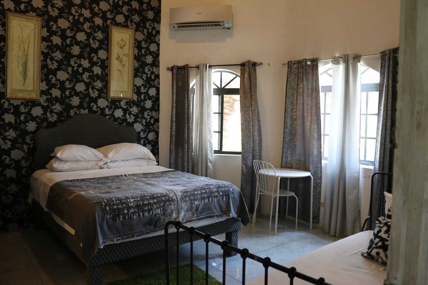 A bedroom with a bed, a chair, a small table, and a window with curtains.