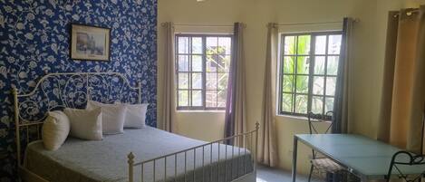 Une chambre Ă coucher avec un lit, un bureau et deux fenĂŞtres.