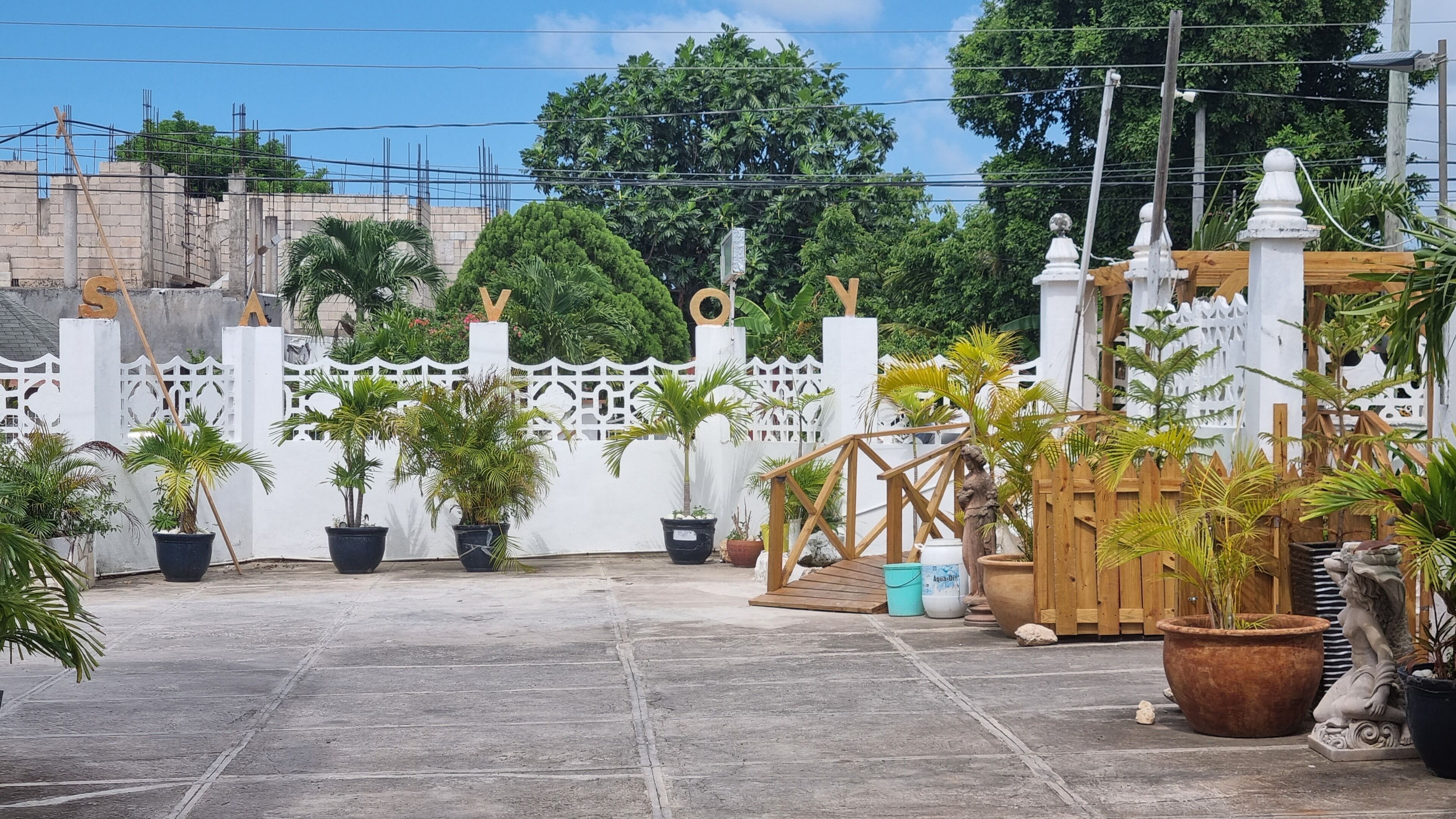 A courtyard with potted plants, a wooden bridge, and a white fence.