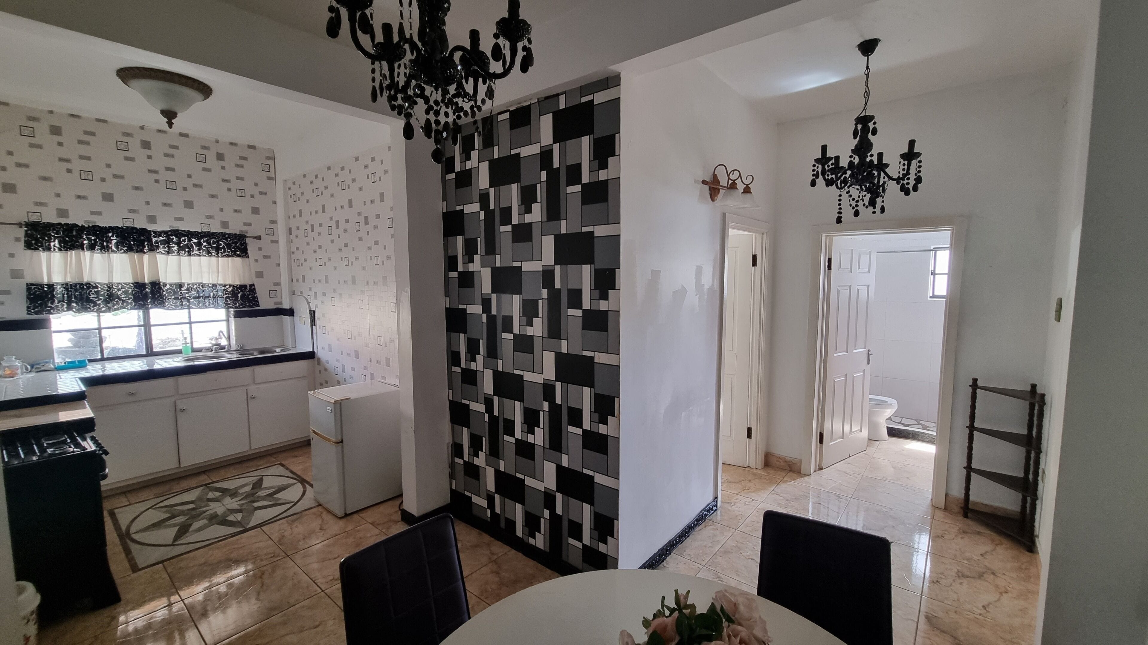 Et moderne køkken med et mønstret backsplash, et spiseområde med bord og stole, samt en lysekrone.