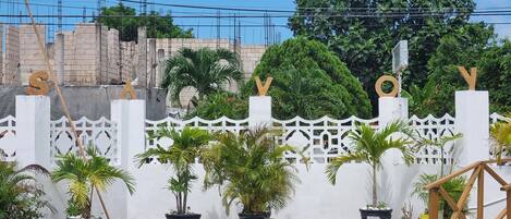 A gated area with potted plants and a white fence with letters 'S' and 'V' on top.