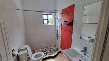 A small bathroom with a toilet, a shower, and a sink.