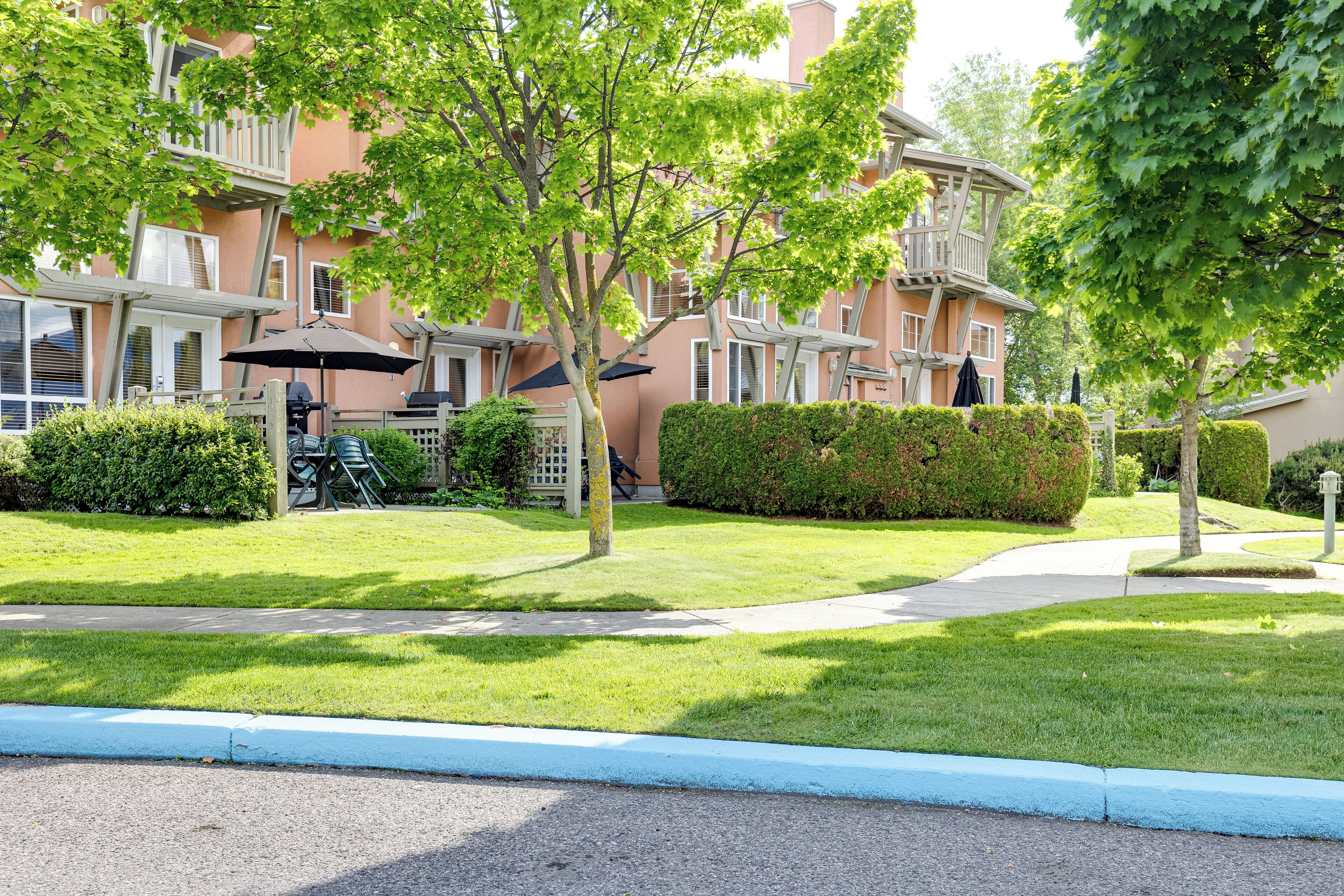 A residential building with a balcony, a lawn, and a pathway.