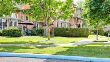 A residential building with a balcony, a lawn, and a pathway.