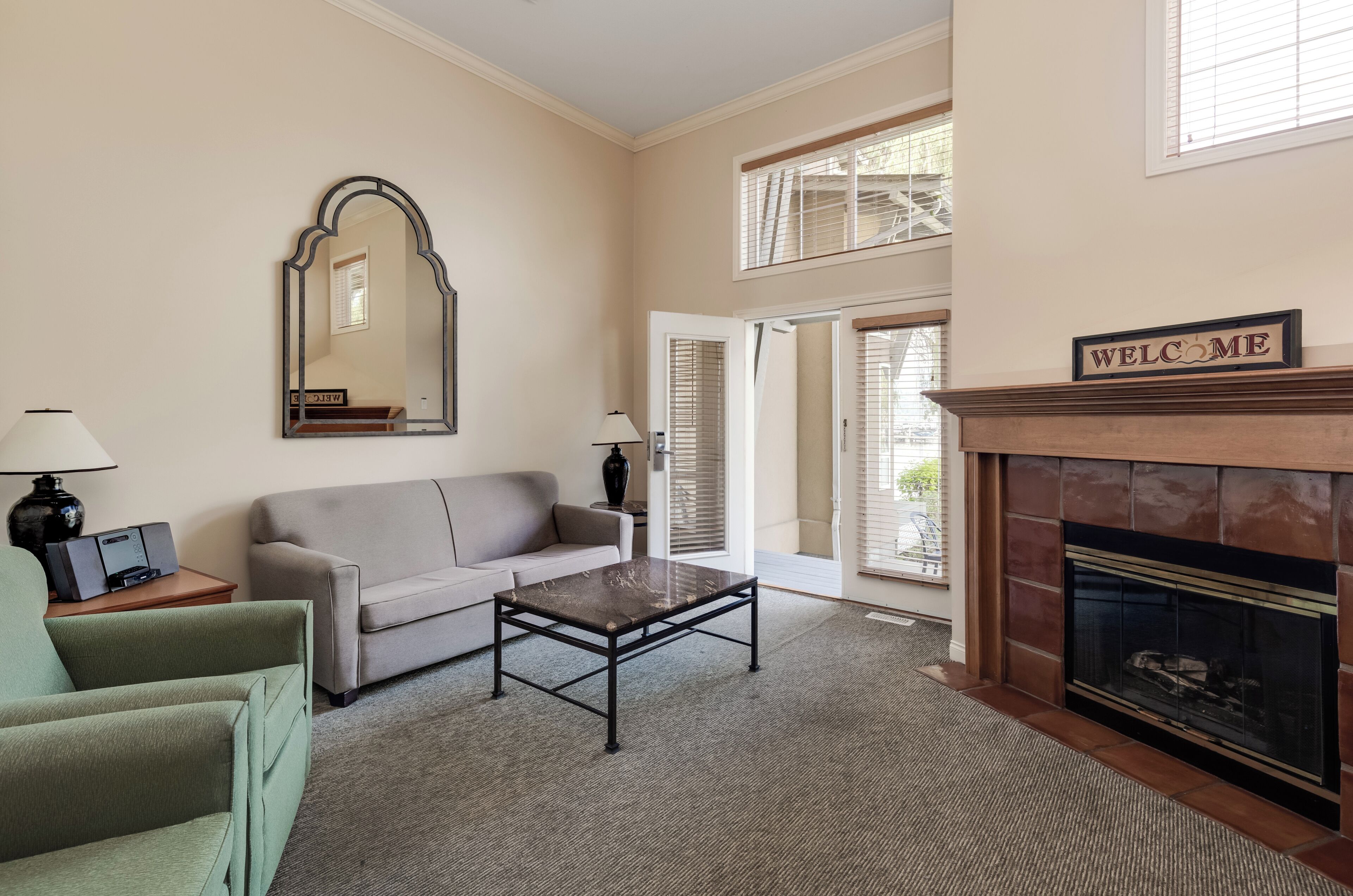 A living room with a sofa, a coffee table, a fireplace, and a mirror.