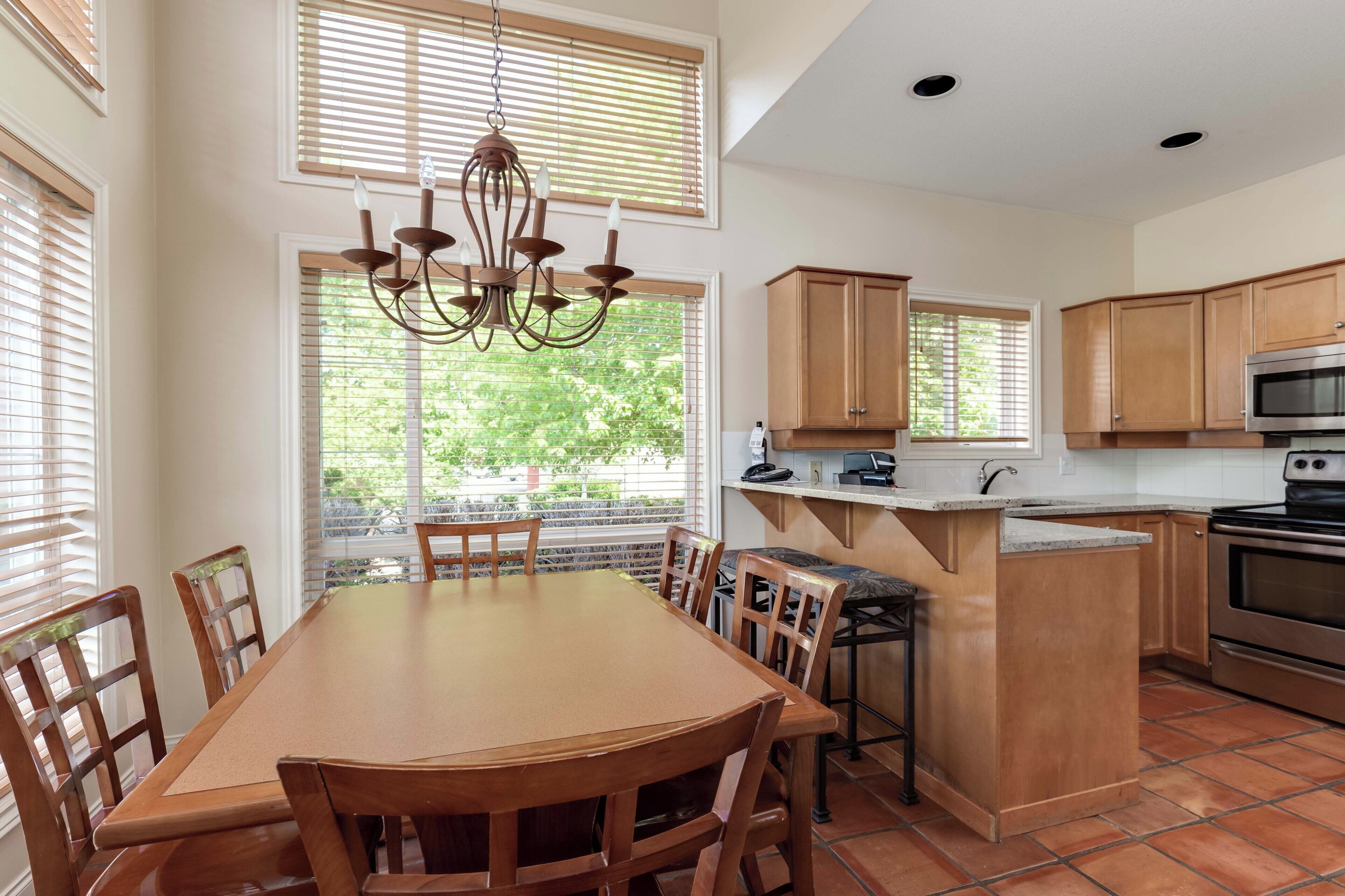 A kitchen with wooden cabinets, a central island, and a dining area with a table and chairs.