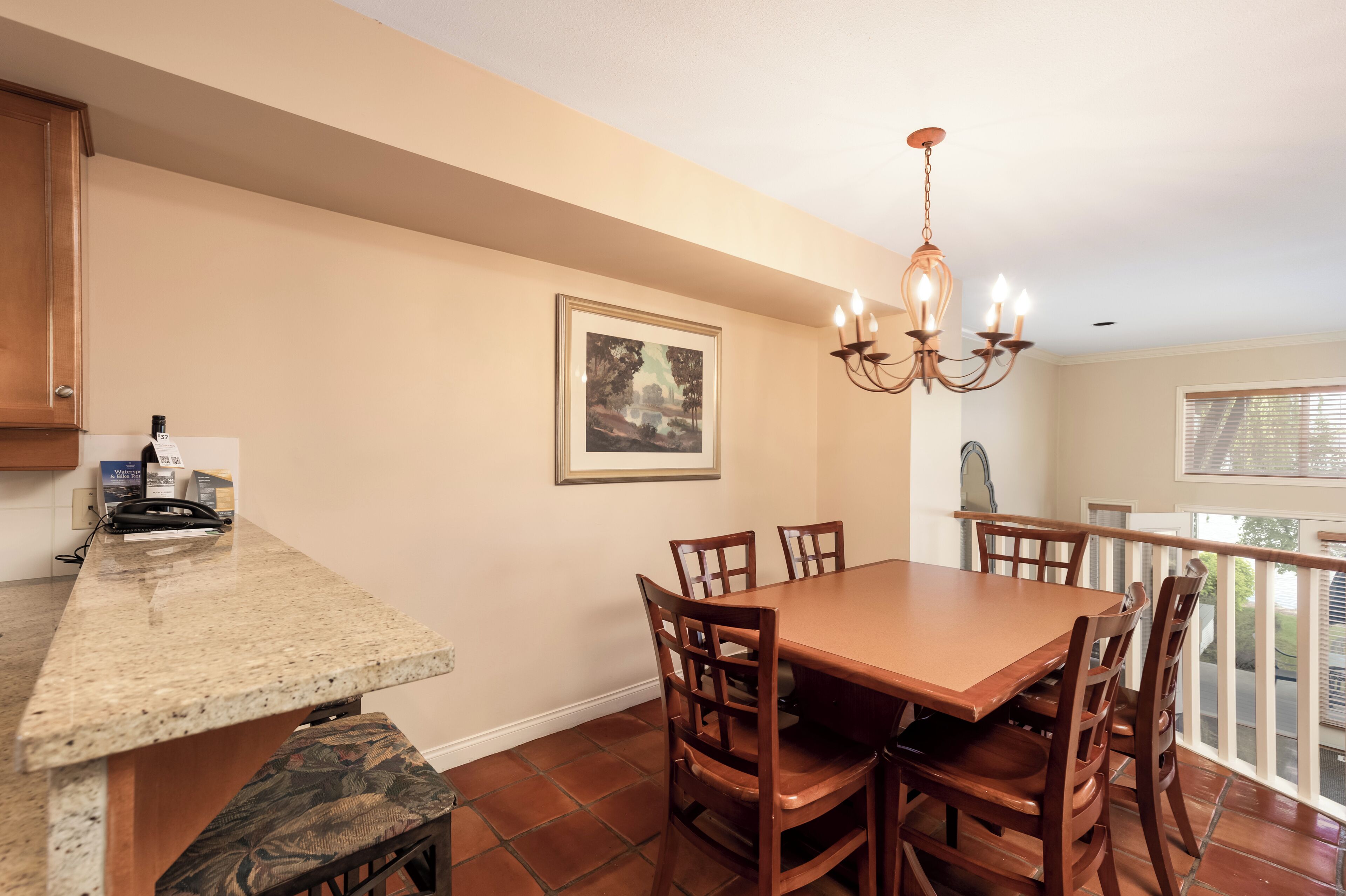 A dining area with a wooden table and chairs, a chandelier, and a framed picture on the wall.