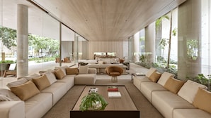 A spacious living area with a large sectional sofa, a coffee table with books, and a view of the outdoors through large windows.