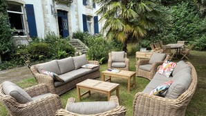 Wicker meubels in een tuin, met een gebouw op de achtergrond.