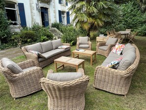 Korbmöbel in einem Garten mit einem Gebäude im Hintergrund.