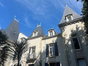 A historic building with multiple towers, a balcony with ornate metalwork, and a stone facade.