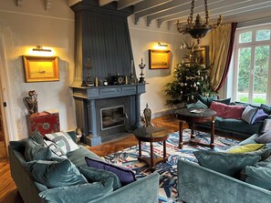 Ein gemütliches Wohnzimmer mit Kamin, Weihnachtsbaum und einer Couch.