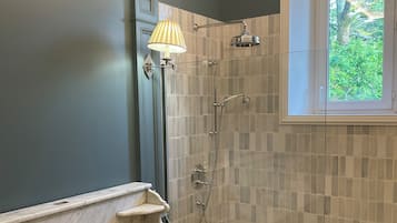 Une salle de bain dotée d’un meuble-lavabo à deux vasques, d’une douche avec une porte en verre et d’une fenêtre laissant entrer la lumière naturelle.