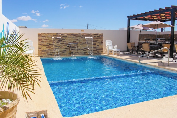 Een buitenzwembad en ligstoelen