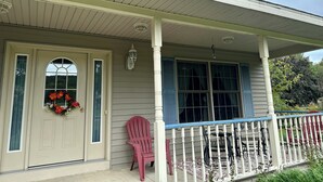 Ein zweistöckiges Haus mit Veranda, einer Tür mit einem Kranz und einem roten Stuhl.