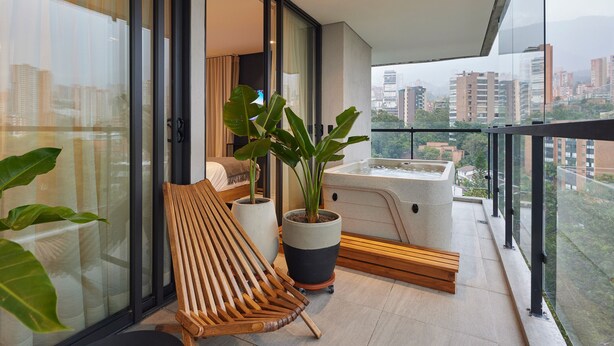 A balcony with a wooden bench, potted plants, and a hot tub. - 2 bedroom, Ac, 300mb, balcony, jacuzzi, wake 1116 (Medellín)
