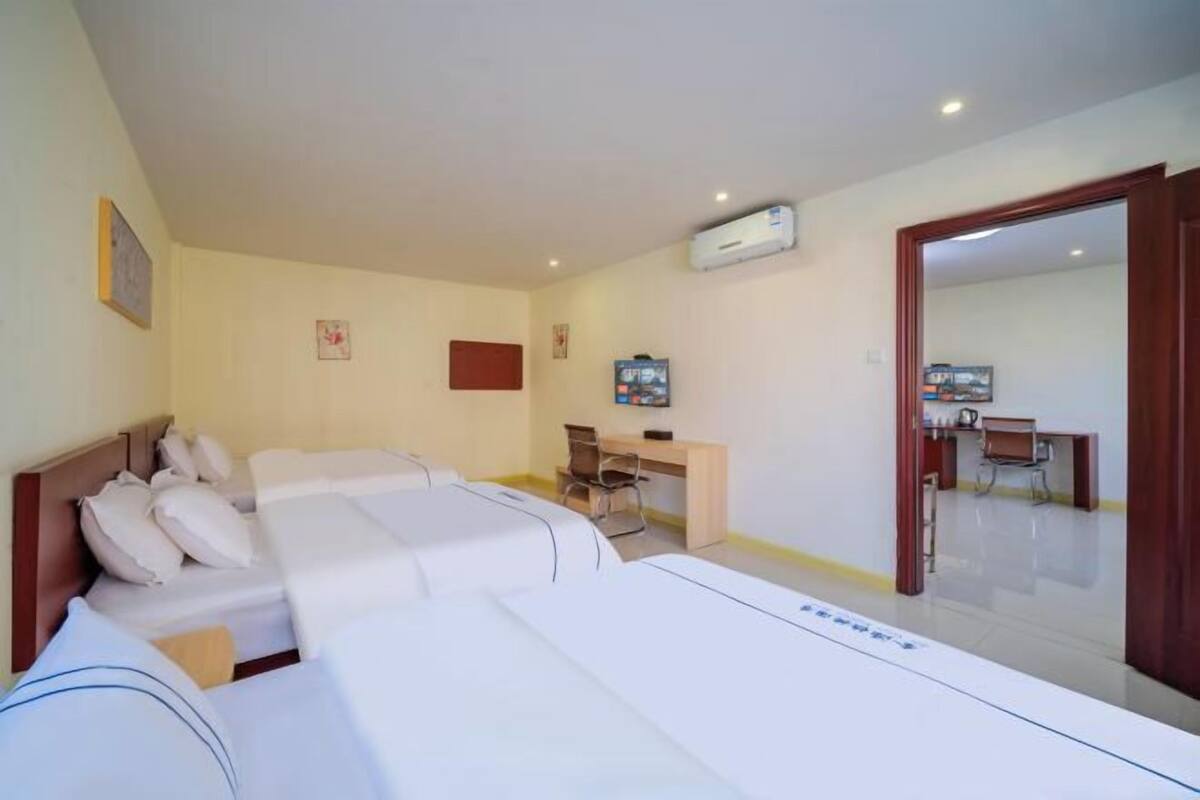 Quarto de hotel com duas camas, uma escrivaninha e uma cadeira.