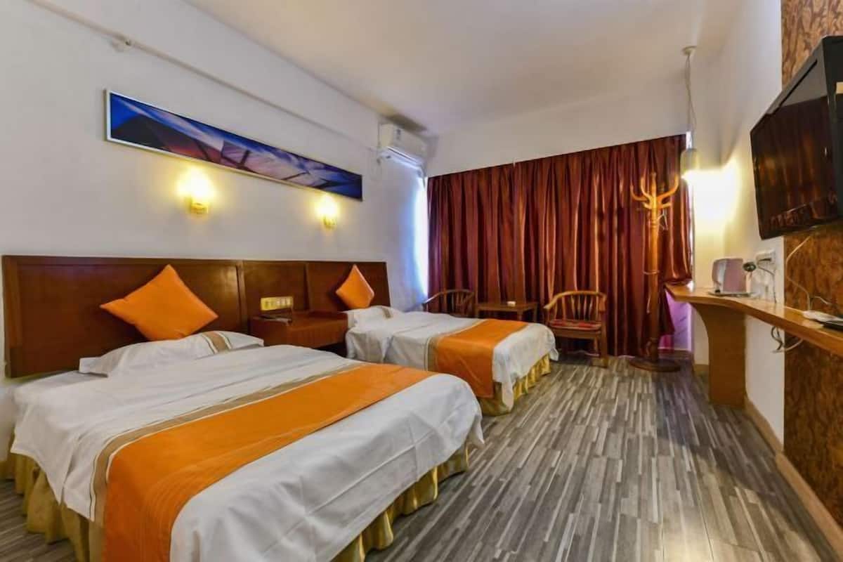 A hotel room with two beds, a wooden headboard, a flat-screen TV, a desk, and a chair.