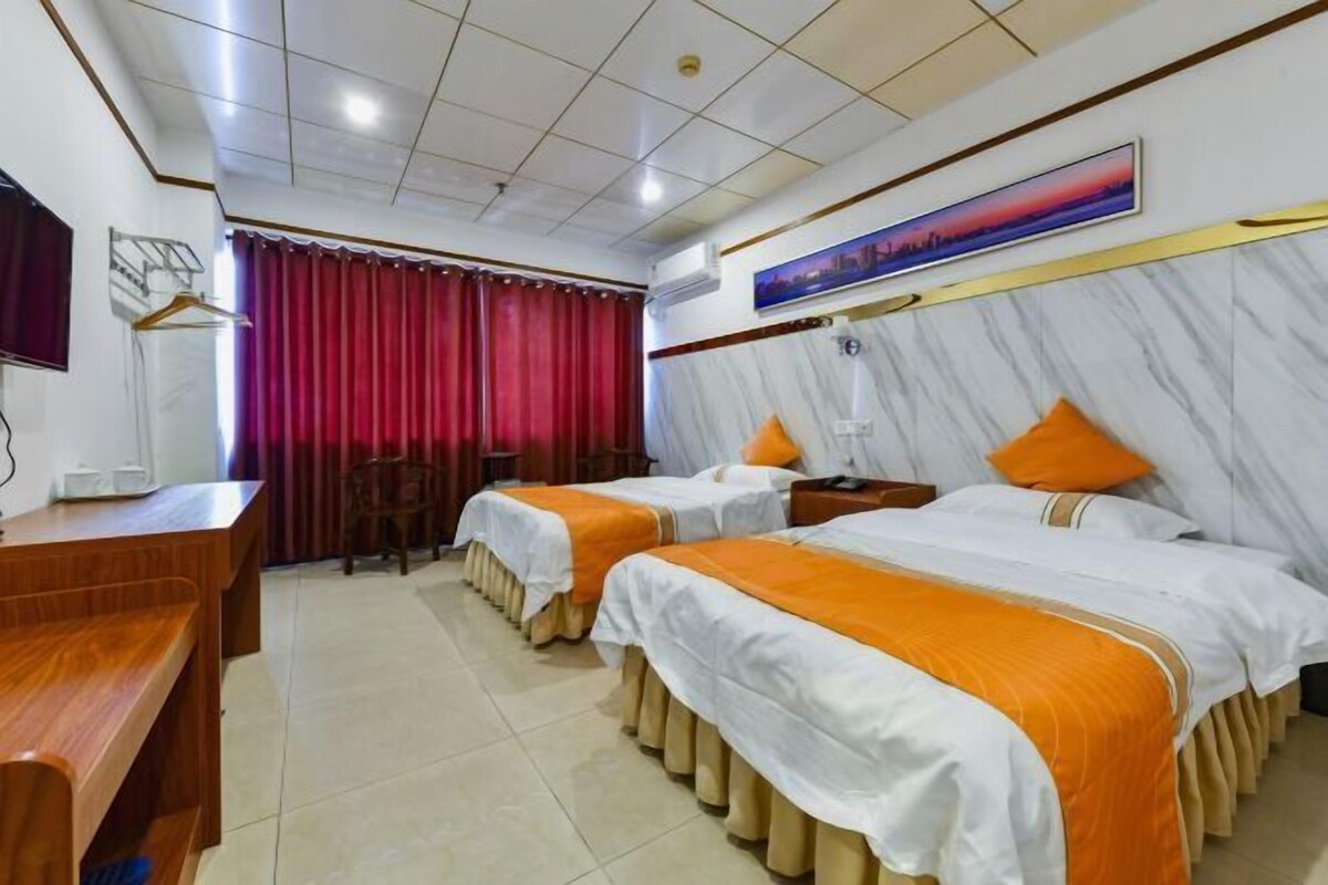 A hotel room with two beds, a desk, and a TV.