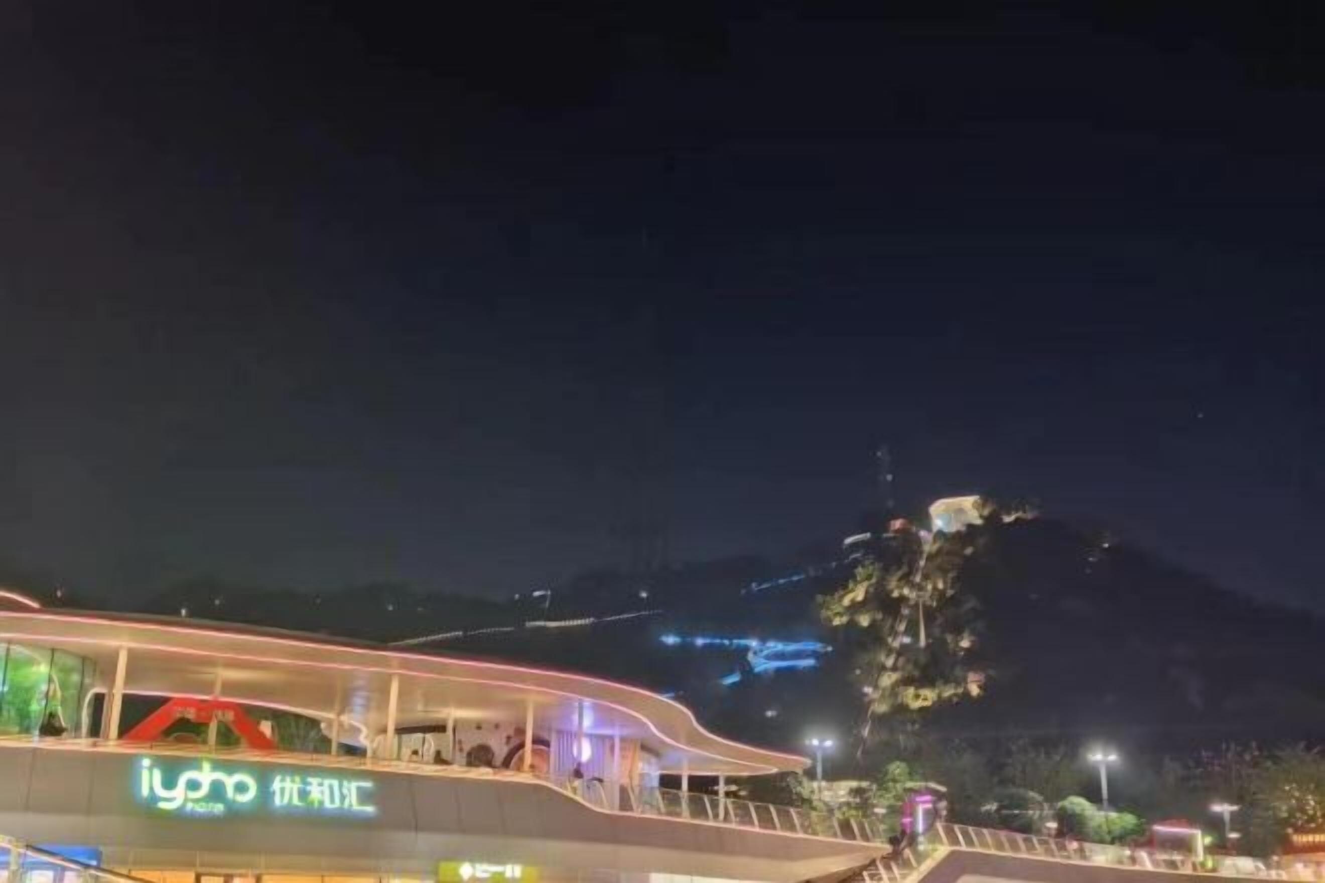 A modern building with a flat roof and a balcony, surrounded by a mountainous landscape.