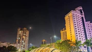 Un edificio alto con ventanas iluminadas y una estructura en forma de cúpula al frente.