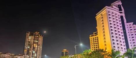 A high-rise building with illuminated windows and a dome-shaped structure in the foreground.