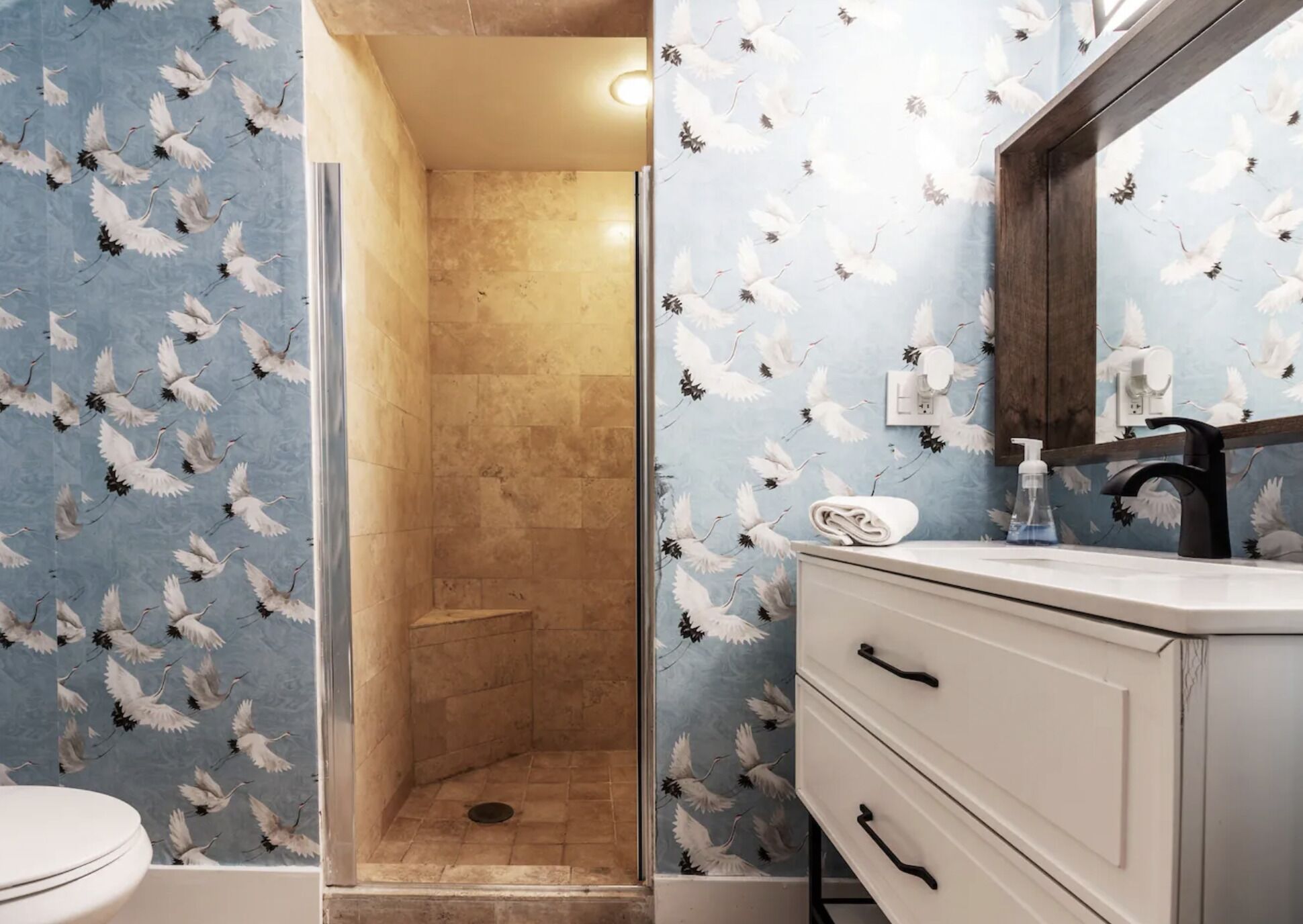 Un bany amb dutxa, un lavabo amb mirall i un vàter.