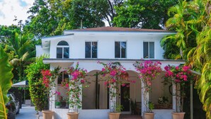 A two-story house with a covered porch, potted plants, and a car parked in front. - Casa Coco: Private Designer Home Pool / Close to Brickell & Coconut Grove (Miami)