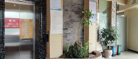 Un vestíbulo con mostrador de recepción, una planta y un tablón de anuncios.