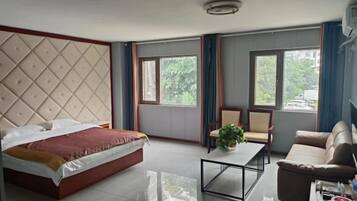 Une chambre d’hôtel avec un lit, une table basse, un canapé et deux fenêtres.