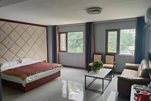 Una habitación de hotel con una cama, una mesita de centro, un sofá y dos ventanas.